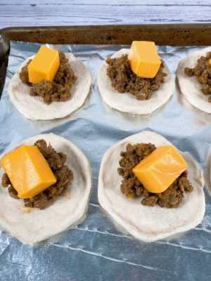 Process shot - ground beef and cheese cubes in the center of each biscuit. 