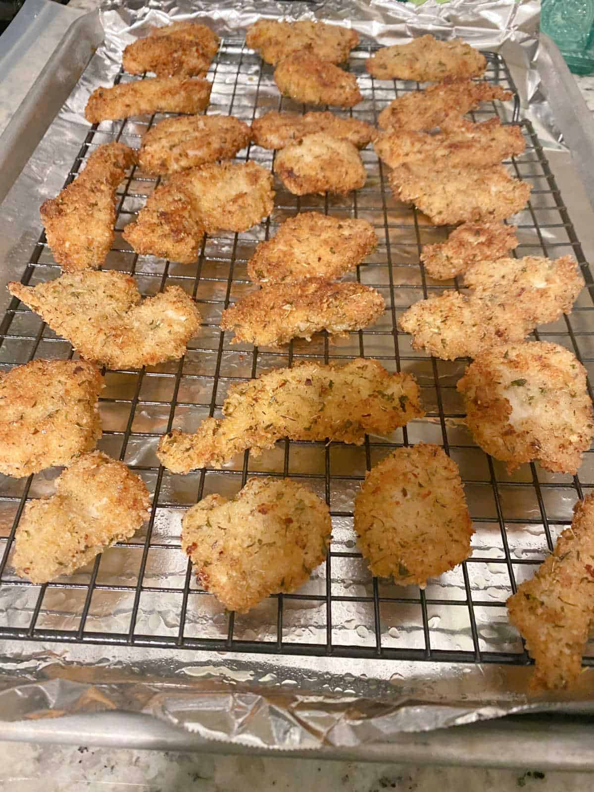 Process shot - pan fried chicken tenders on baking sheet ready to be finished in the oven. 