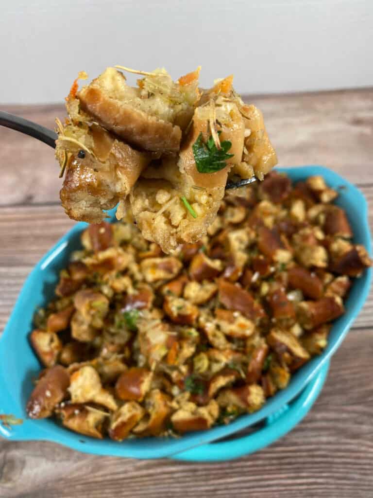 Forkfull of stuffing held up to the camera with casserole dish of stuffing below.