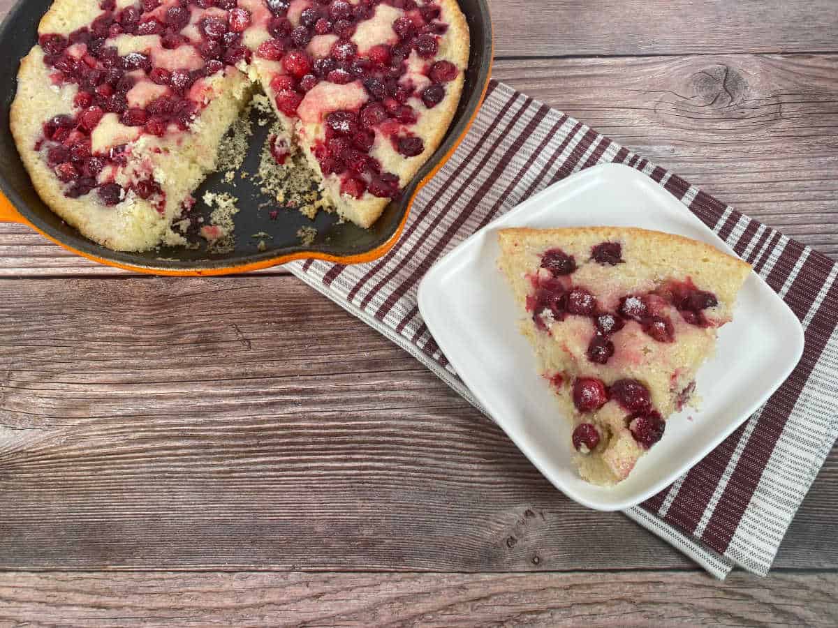 slice of cobbler sits on a white plate with dish next to it.