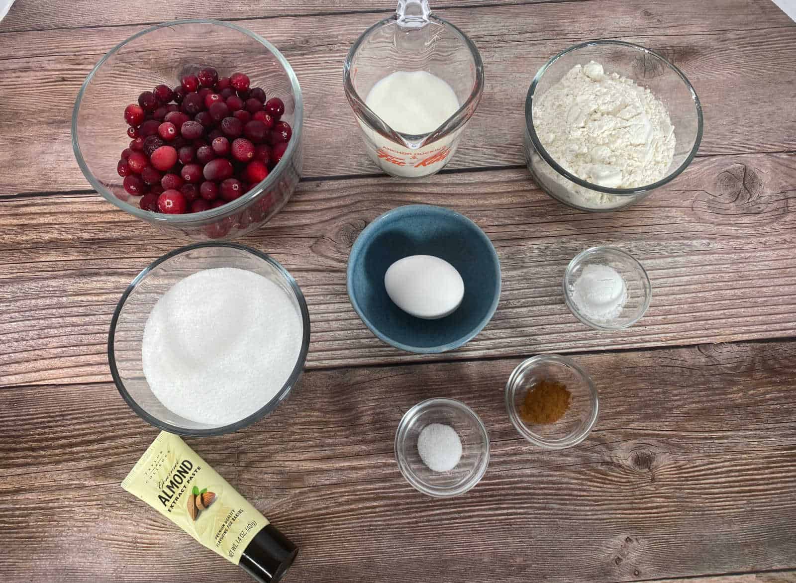 Ingredients for cobbler sit in glass dishes on a wooden background. 