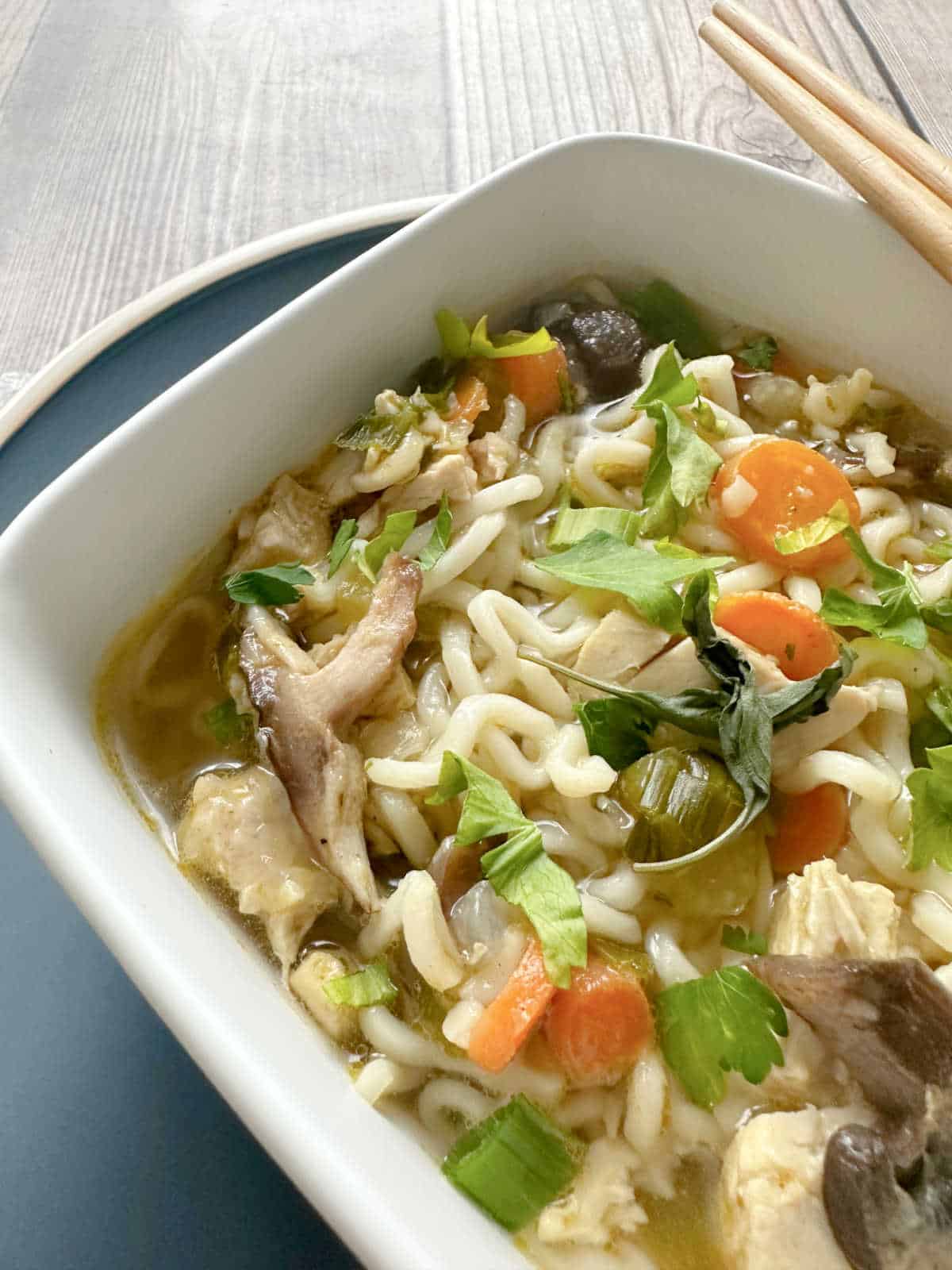 close up of soup in a square white bowl.