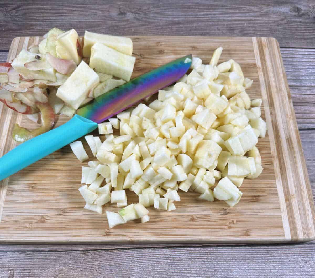 Process shot - Diced apples sit on a cutting board. 