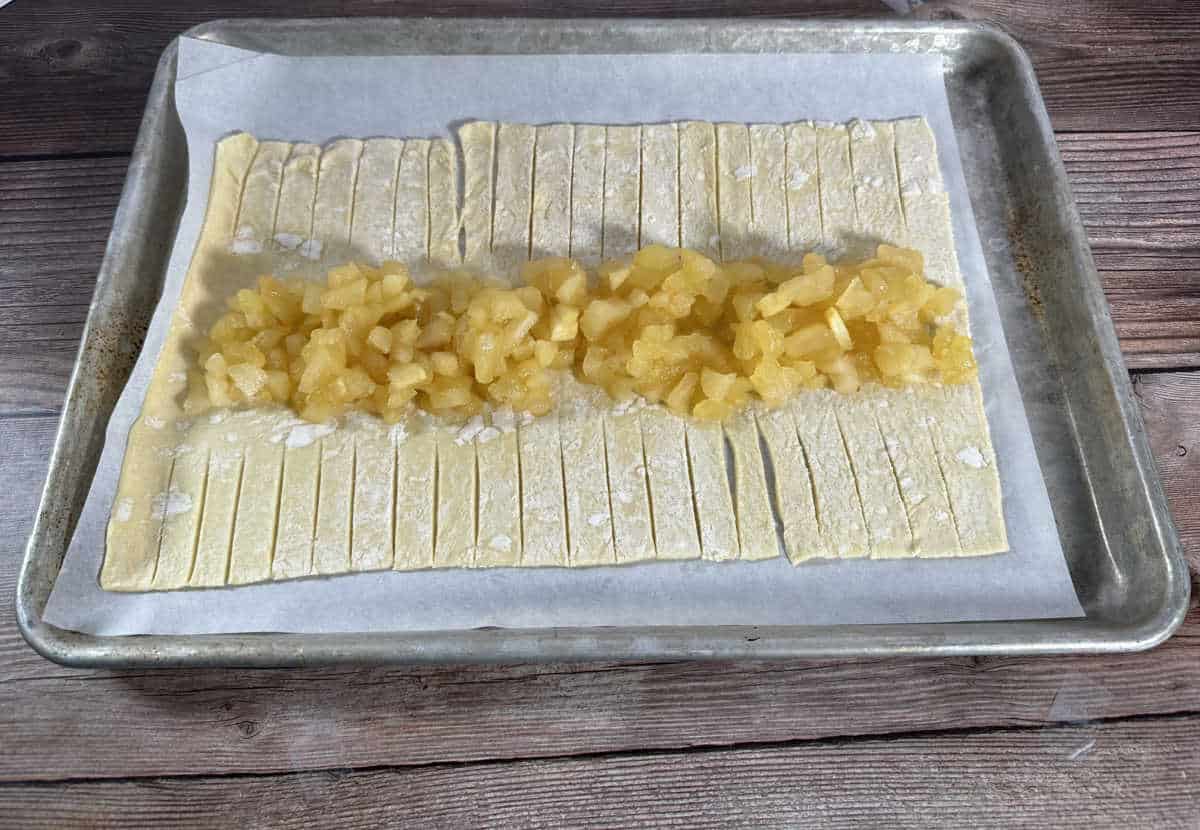 Process shot - apples down the center of puff pastry. 