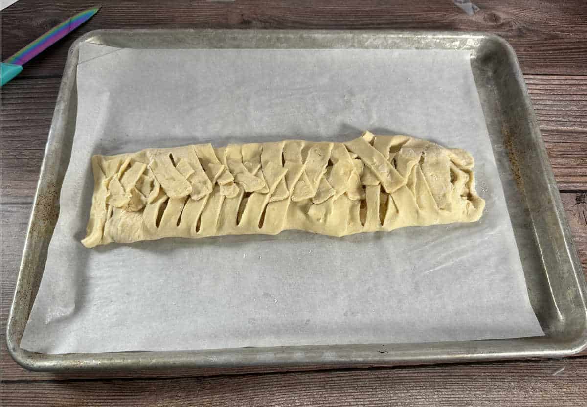 Process shot - braided pastry sitting on a parchment lined baking sheet. 