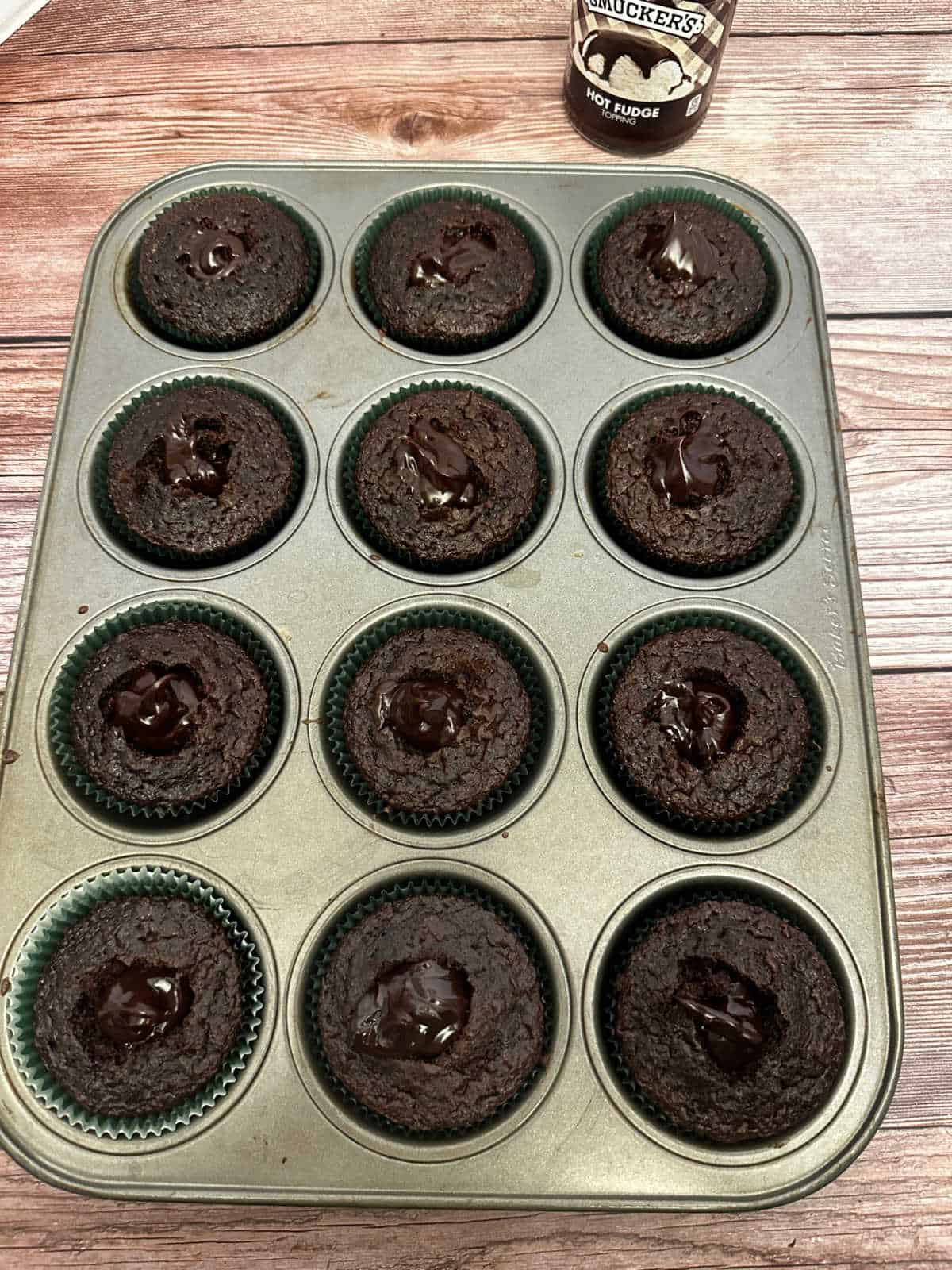 Process shot - Cupcakes in pan filled with hot fudge sauce. 