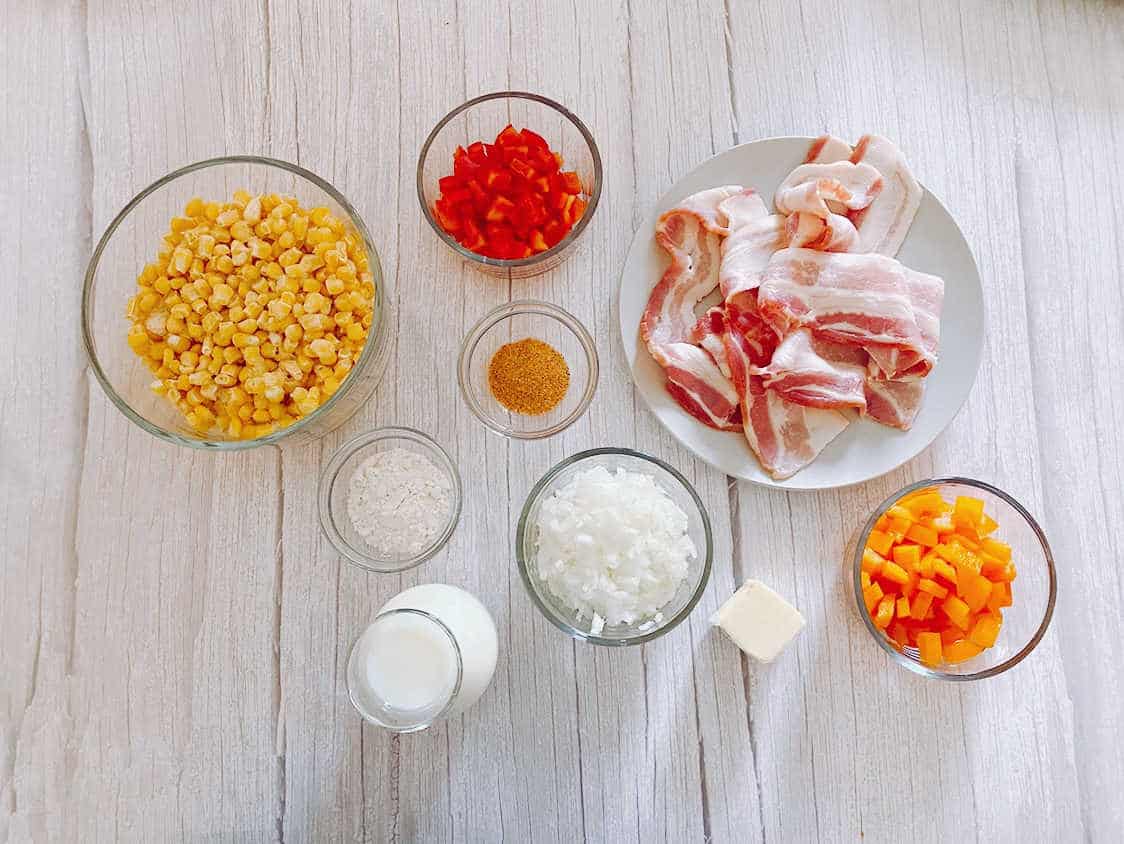 Ingredients sit in glass bowls on a white wooden background. 