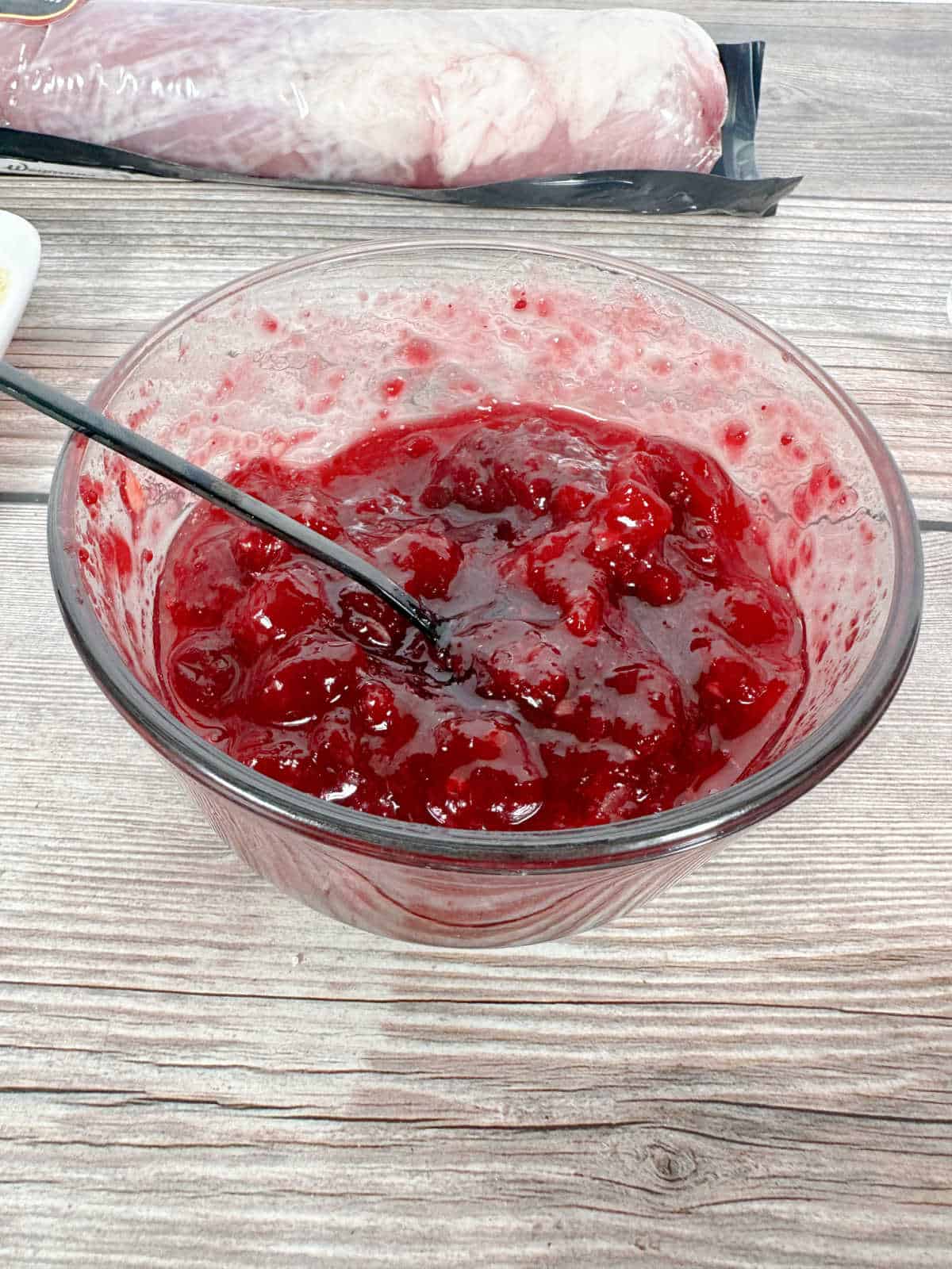 Process shot - cranberry sauce in glass bowl with ginger paste stirred in.