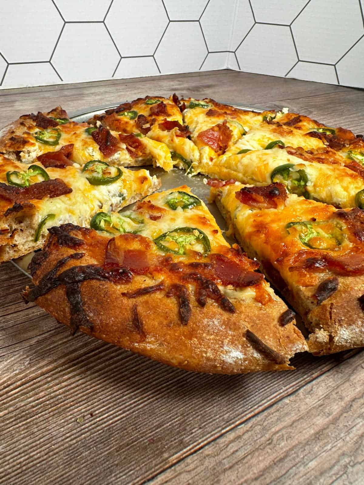 Close up image of pizza to show golden cheese and sliced jalapenos. 