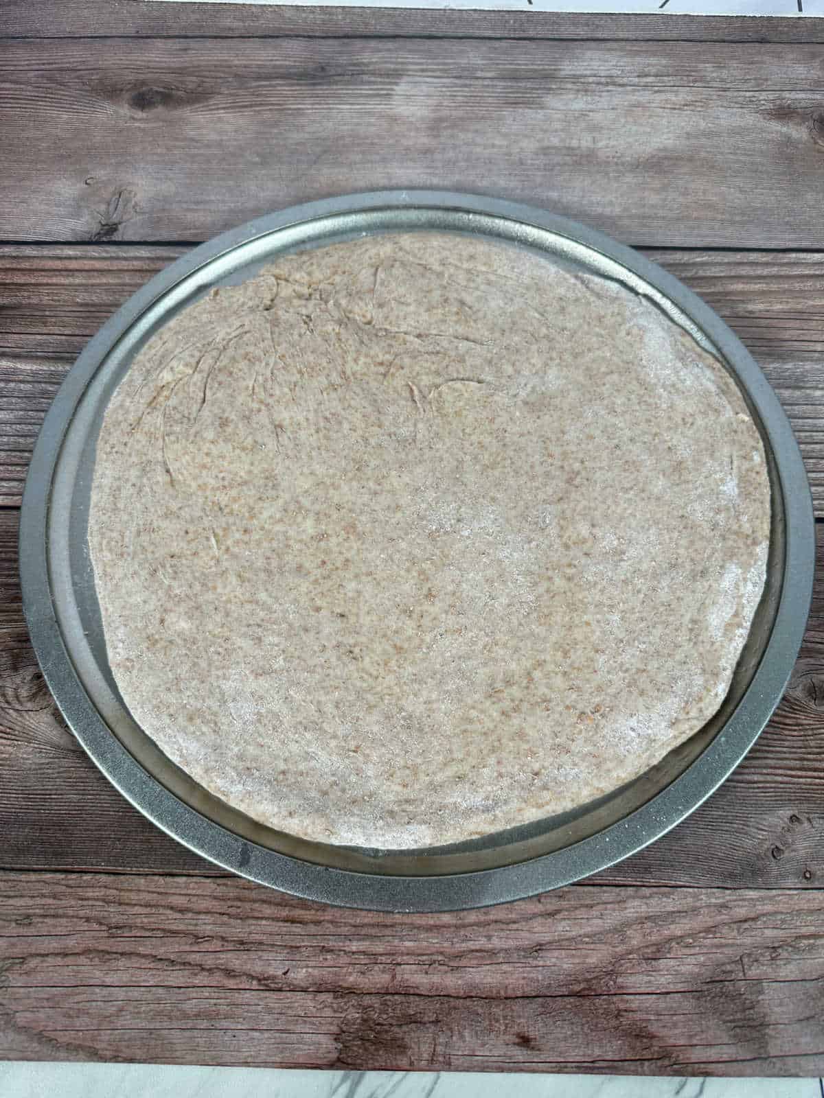 Process shot - pizza dough on a round pizza pan. 