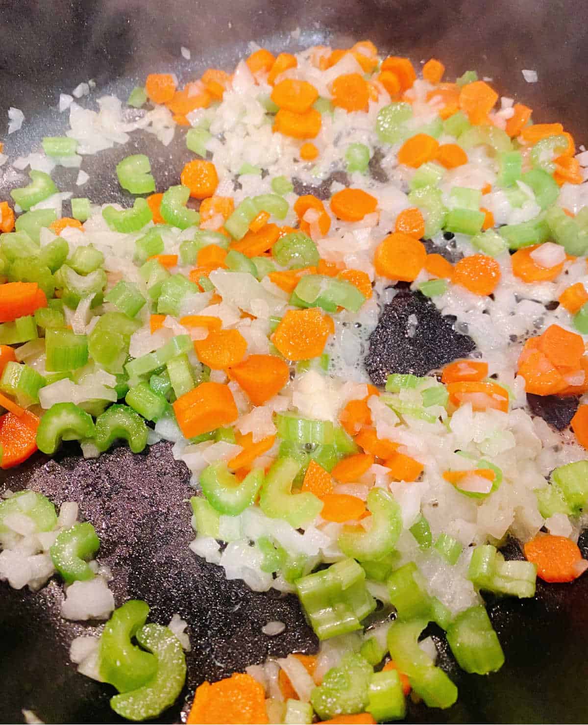 Process shot - onions, celery and carrots cooking in a pot. 