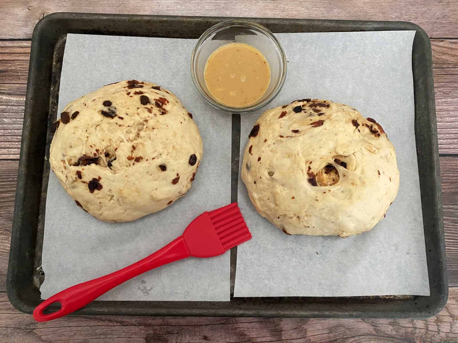 Process shot - dough balls brushed with egg/vanilla mixture sitting on parchment sheet. 