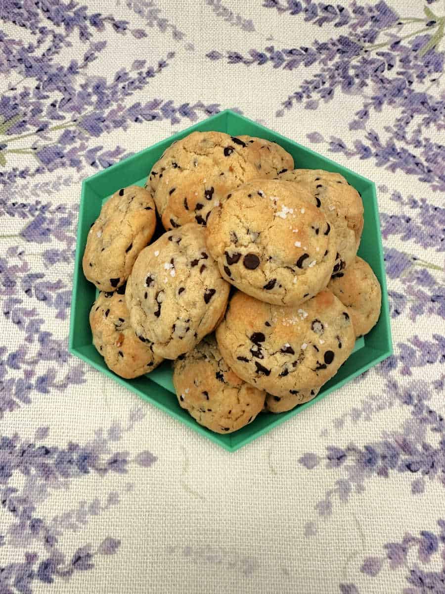 Overhead image of cookies stacked on a green platter sitting on a lavender printed cloth. 