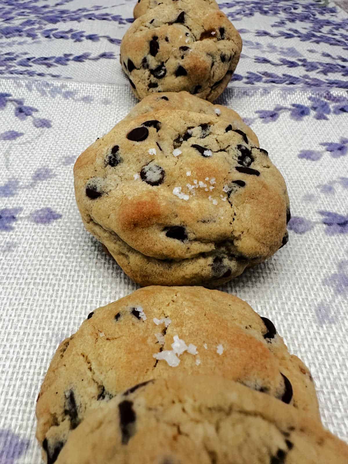 Row of cookies lined up on a lavender printed cloth. 