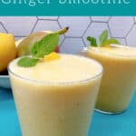 Yellow-colored smoothies are in short glasses, garnished with lemon slice, mango piece and fresh mint on teal napkin.