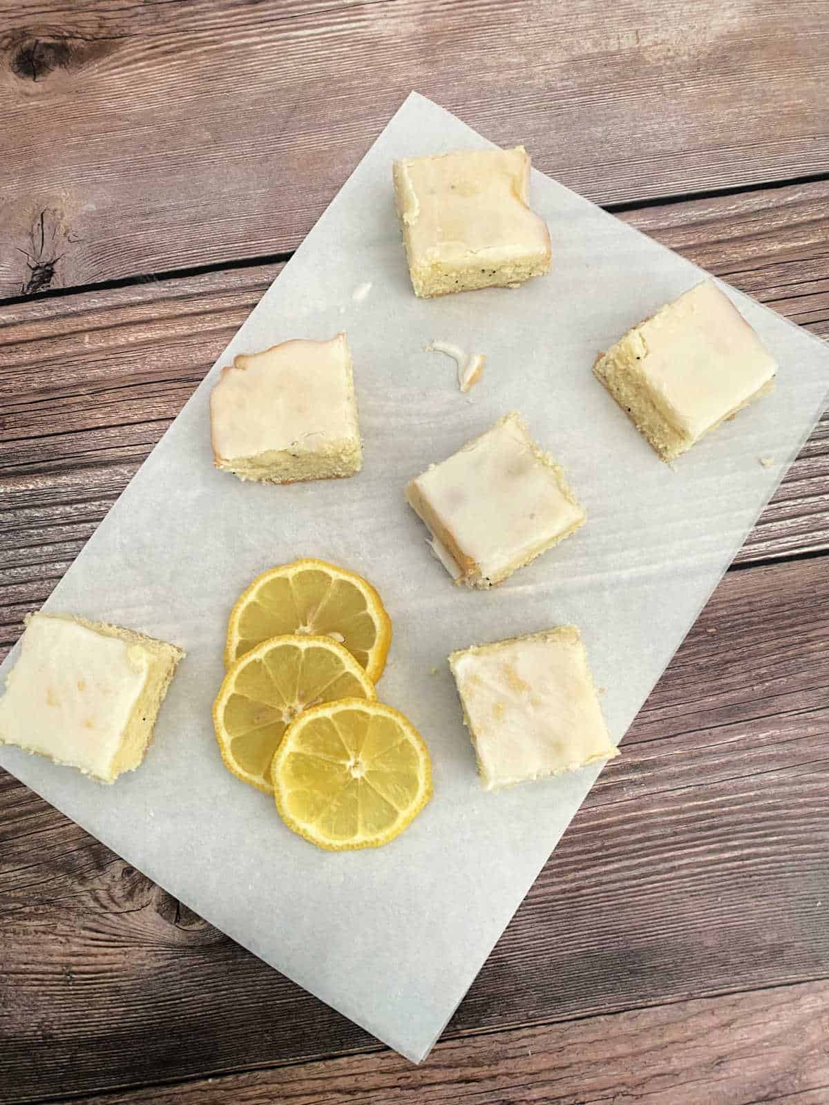 Overhead images of sliced bars and lemon slices on a piece of parchment paper on a wooden background. 