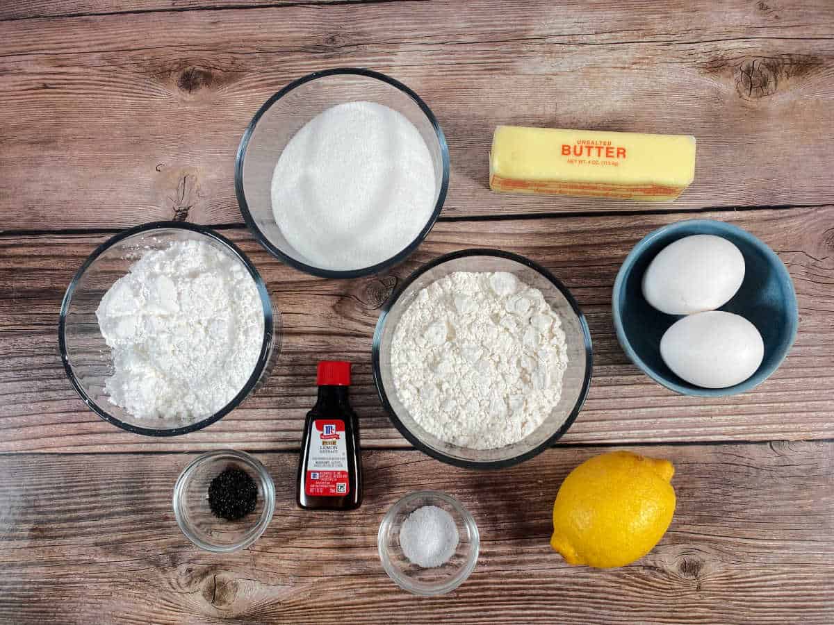 Ingredients for the recipe sit in glass containers on a wooden background. 