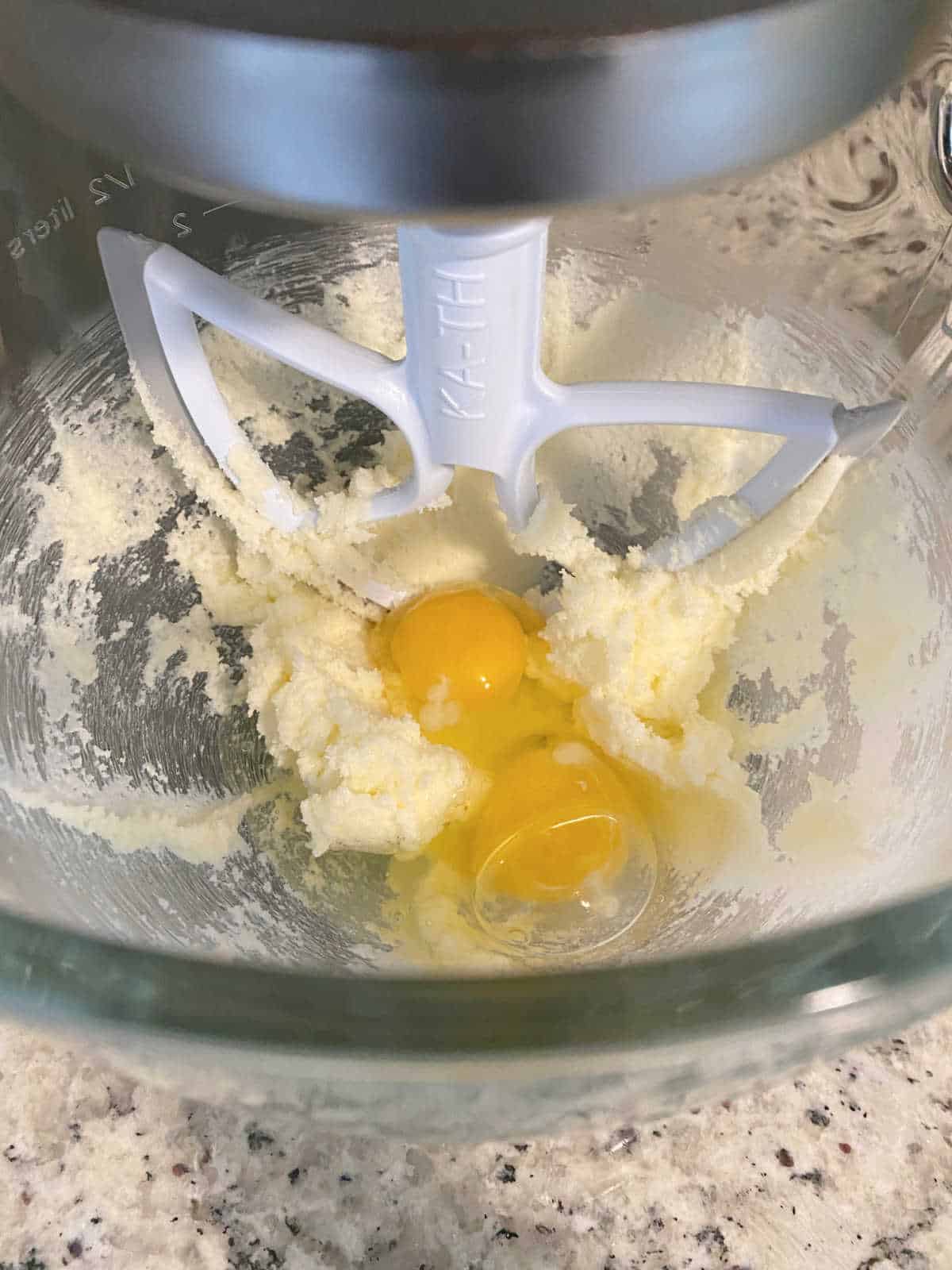 Process shot - eggs added to the glass bowl of a stand mixer. 