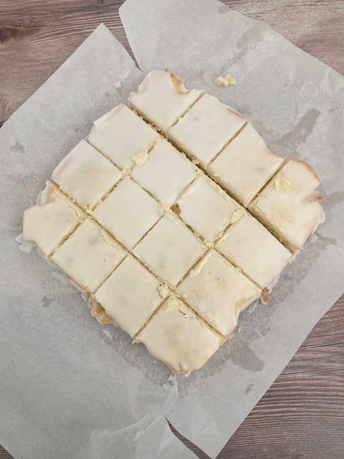 Process shot - lemon bars on parchment paper sliced into squares. 