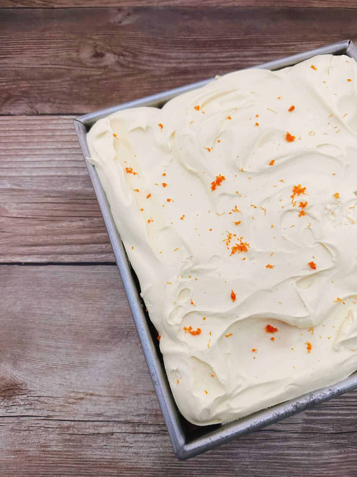 Cake, garnished with orange zest on a wooden background. 