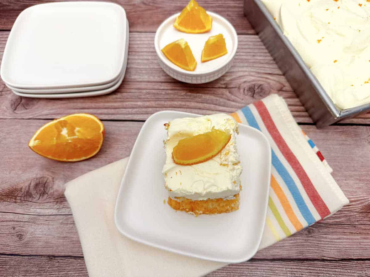 Cake sits on wooden background ready to be garnished with orange slices and served. 