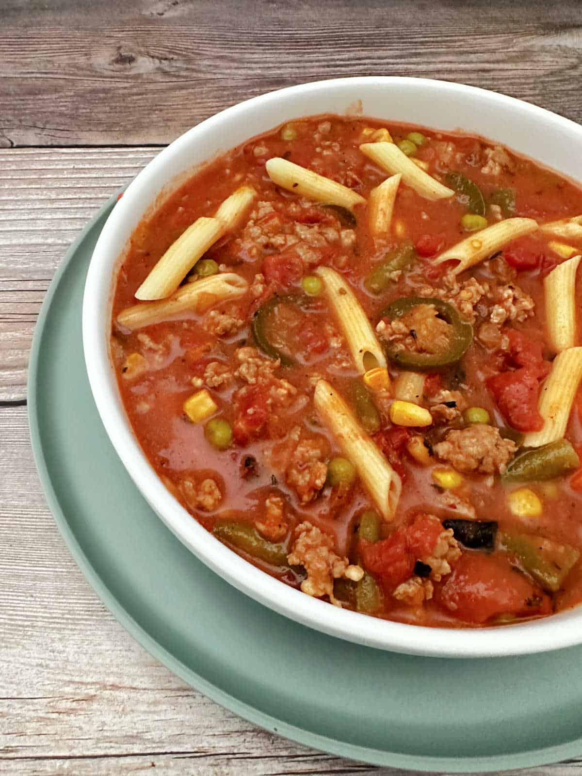 Close up image of soup in a shallow white bowl showing all of the ingredients.