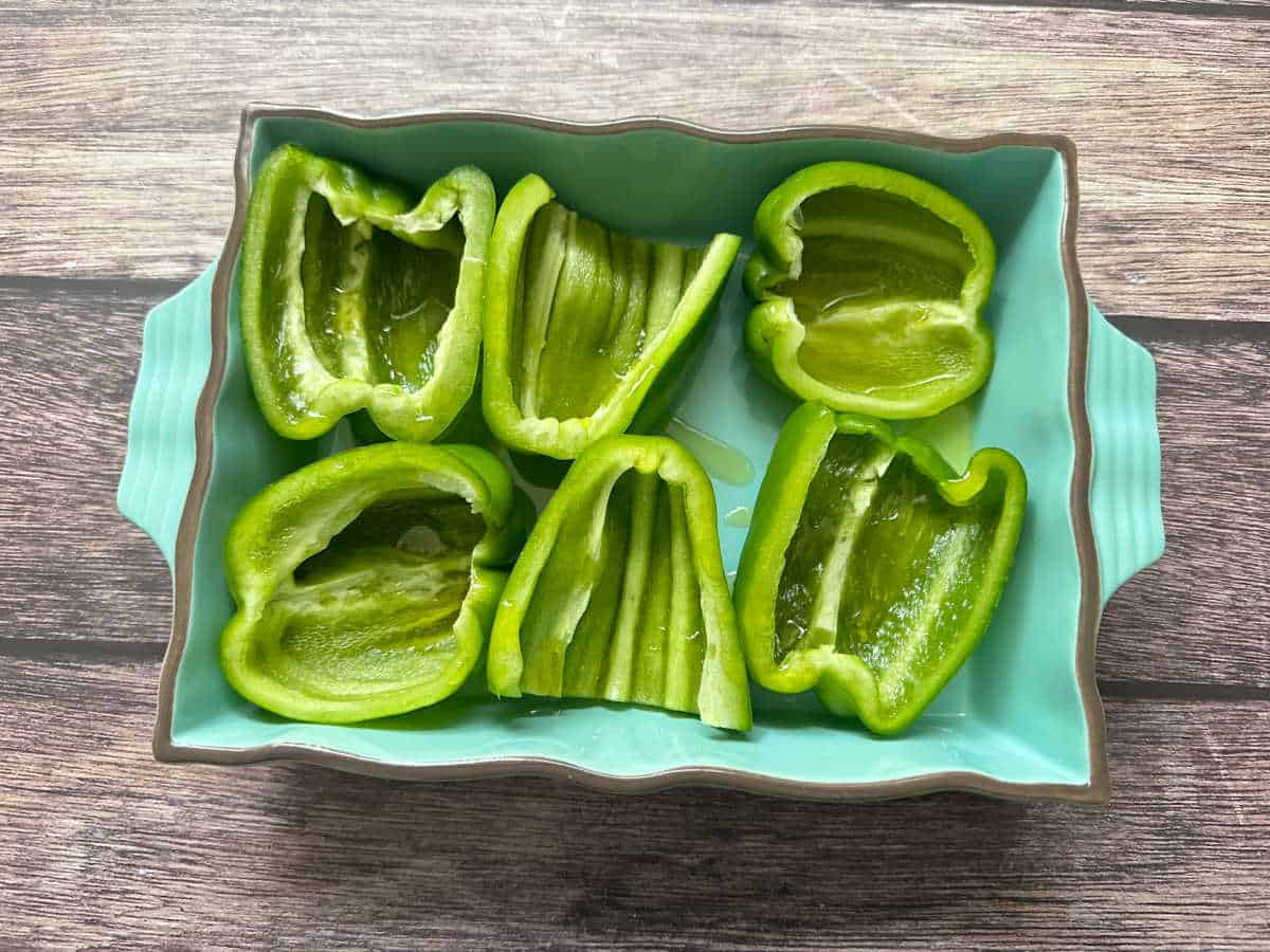 Process shot - halved bell peppers in a baking dish. 