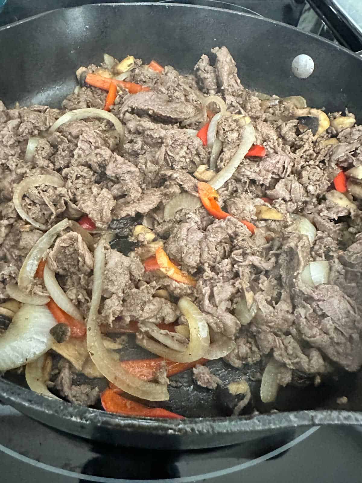 Process shot - steak and vegetables back in skillet together. 