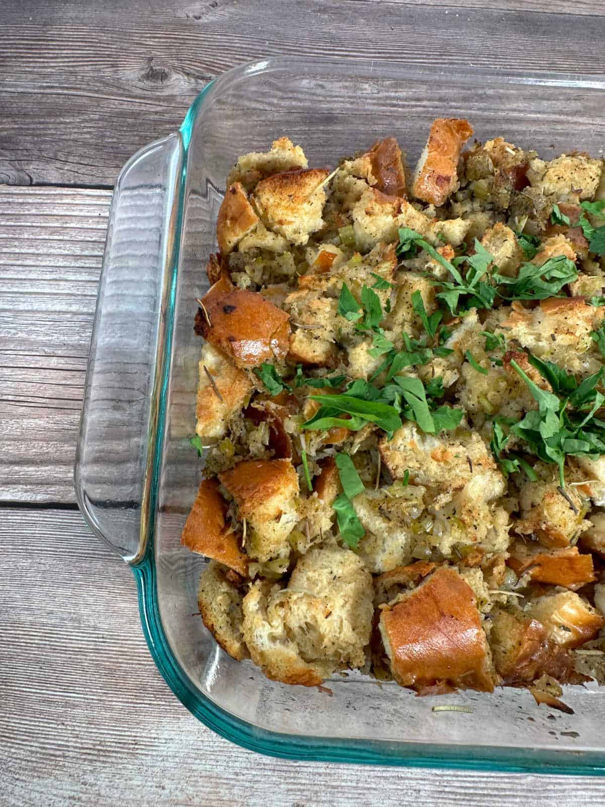 Baked stuffing, garnished with fresh chopped parsley in a baking dish. 