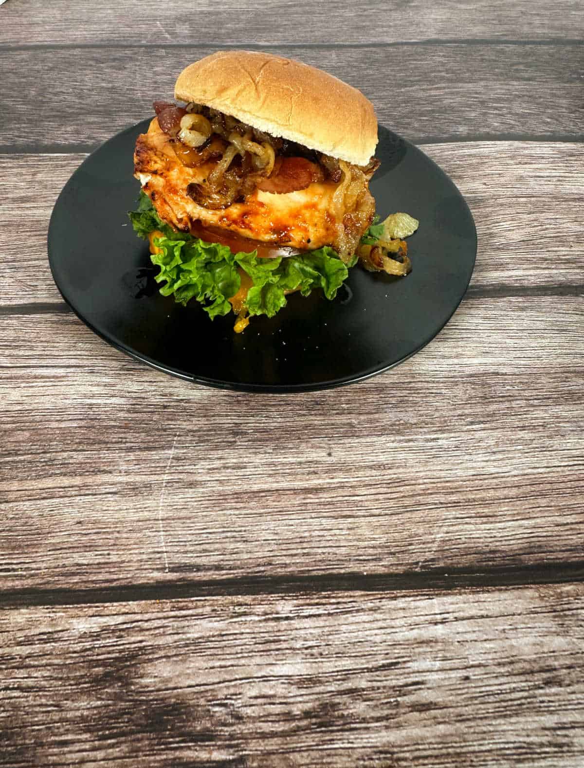 Assembled sandwich sits on a black plate on a wooden background.