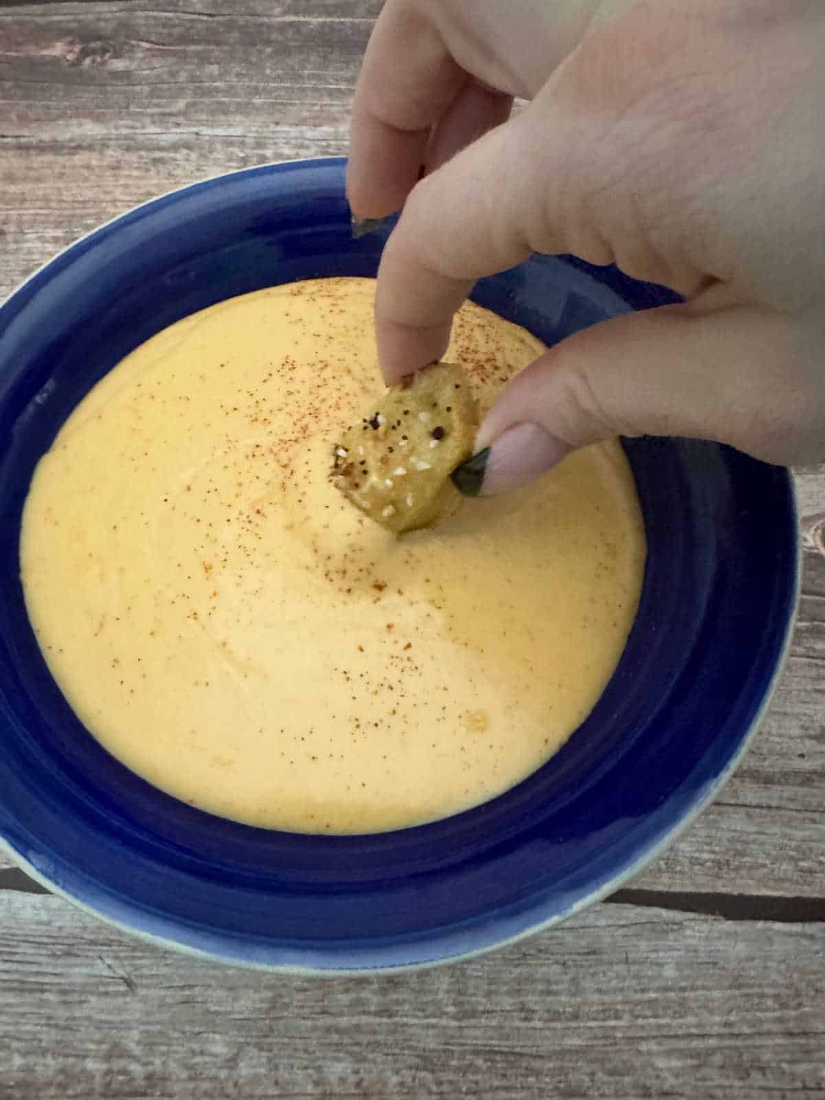 Soft pretzel being dipped in the cheese sauce. 