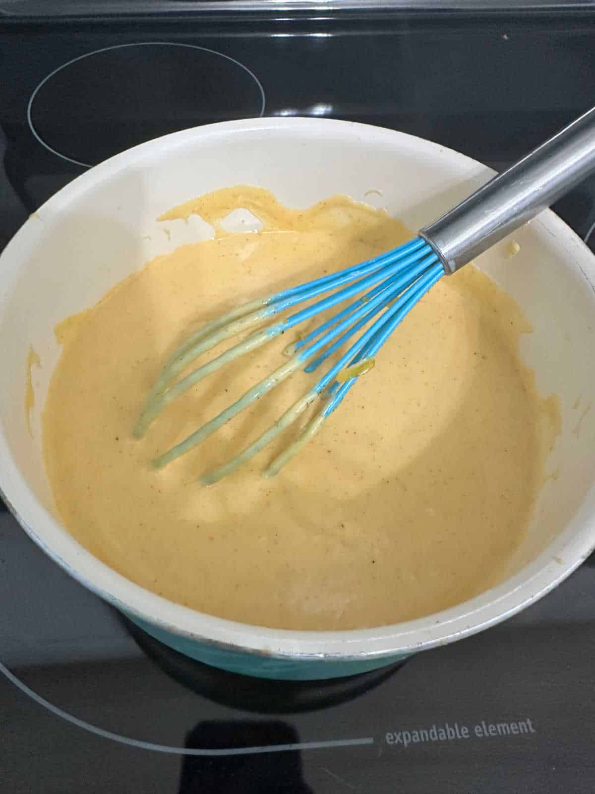 Process photo - whisking cheese sauce until it thickens in the saucepan. 