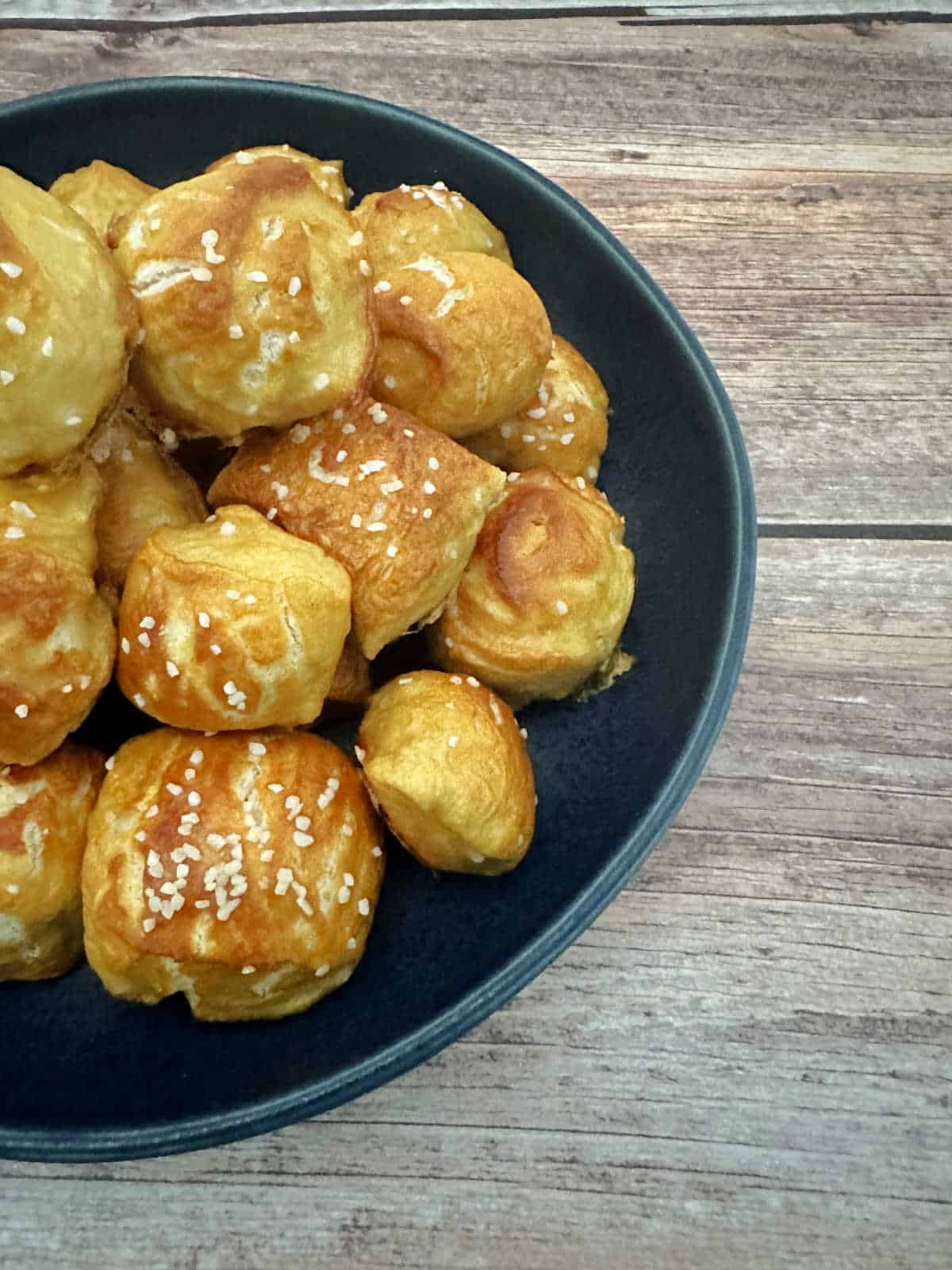 Pretzel bites stacked on a round plate on a wooden bckground. 