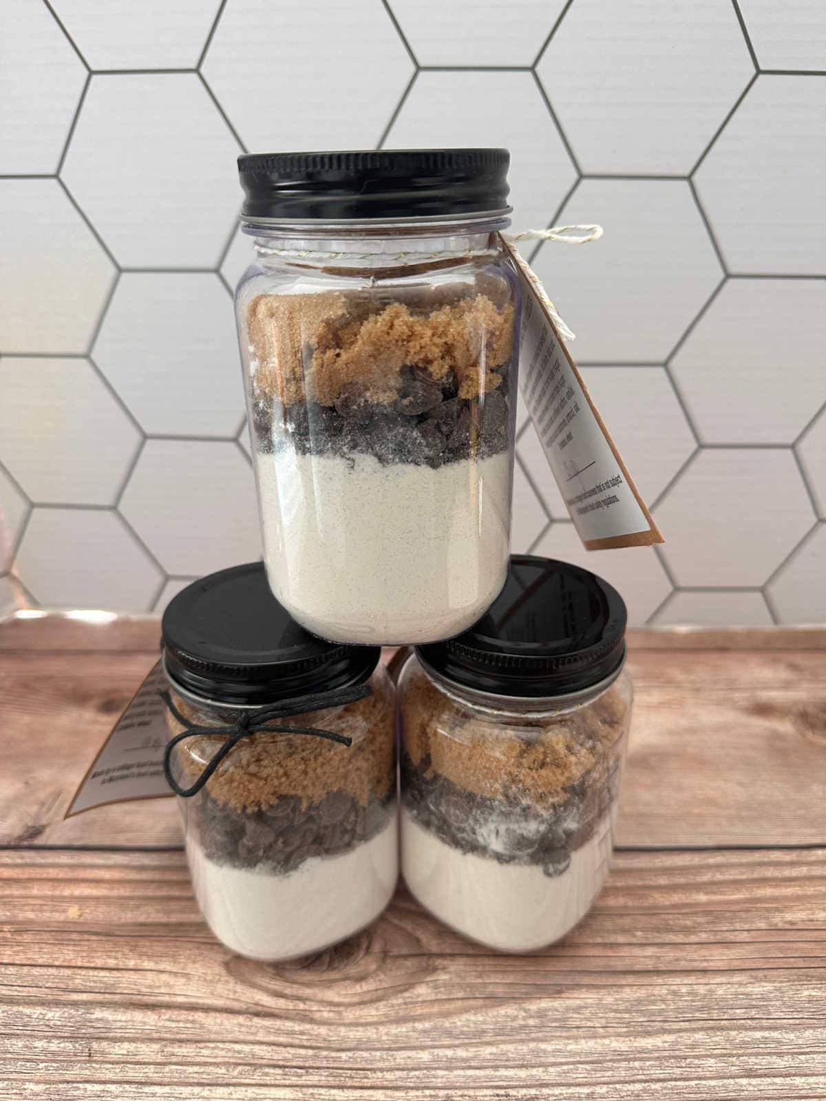 Stack of 3 mason jars filled with chocolate chip cookie mix.
