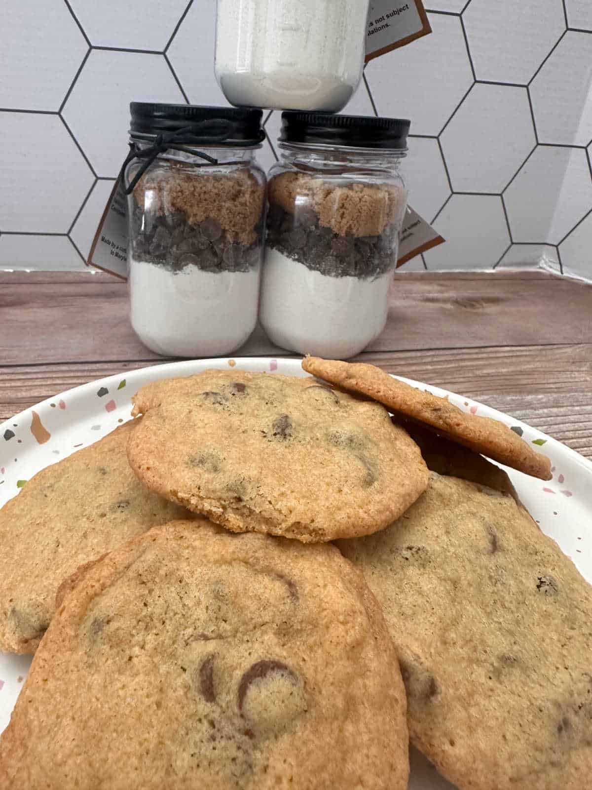 Plate of baked cookies with jars of cookie mix in the background. 