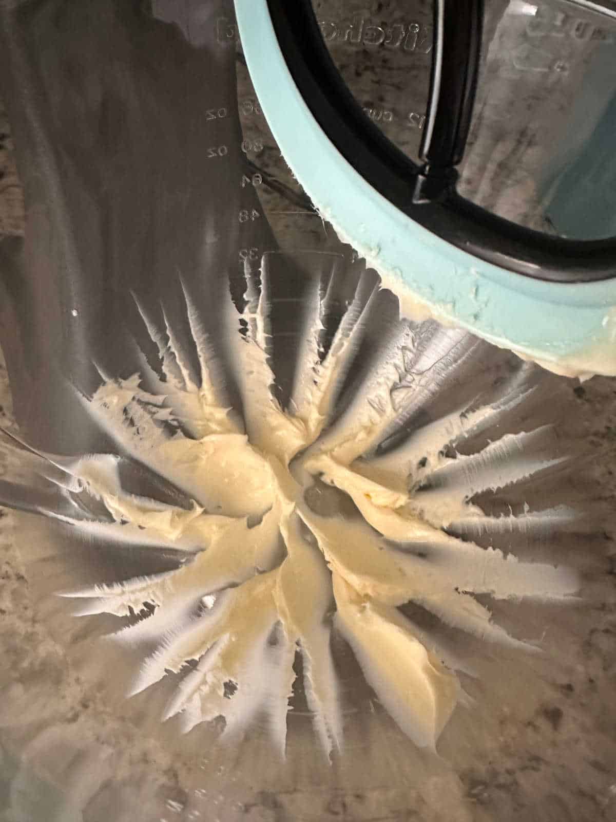 Close up image of beaten butter in a stand mixer. 