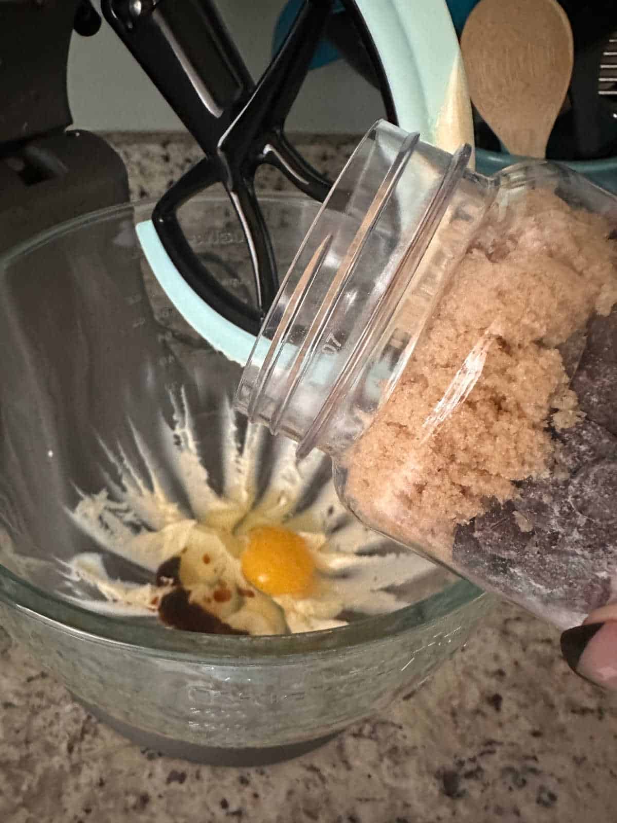 Close up image of vanilla and egg added, cookie mix about to be poured into mixer. 